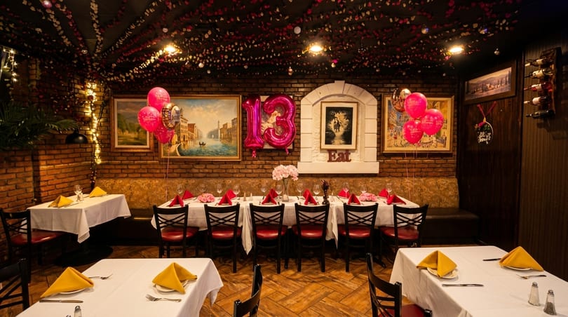 Restaurant dining room decorated for a 13th birthday party with pink balloons and table settings.